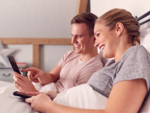 Paar im Bett, das zusammen auf dem Handy liest