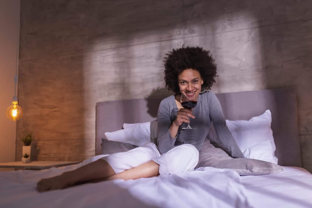 Frau trinkt Wein im Bett