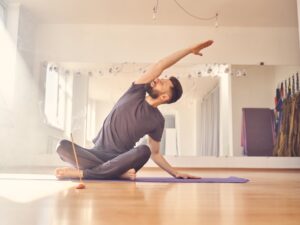 Hübscher junger Mann macht Dehnübungen im Yoga-Studio