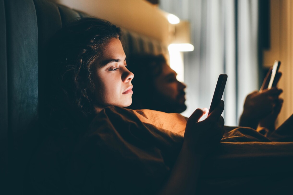 Paar mit Smartphones im Bett